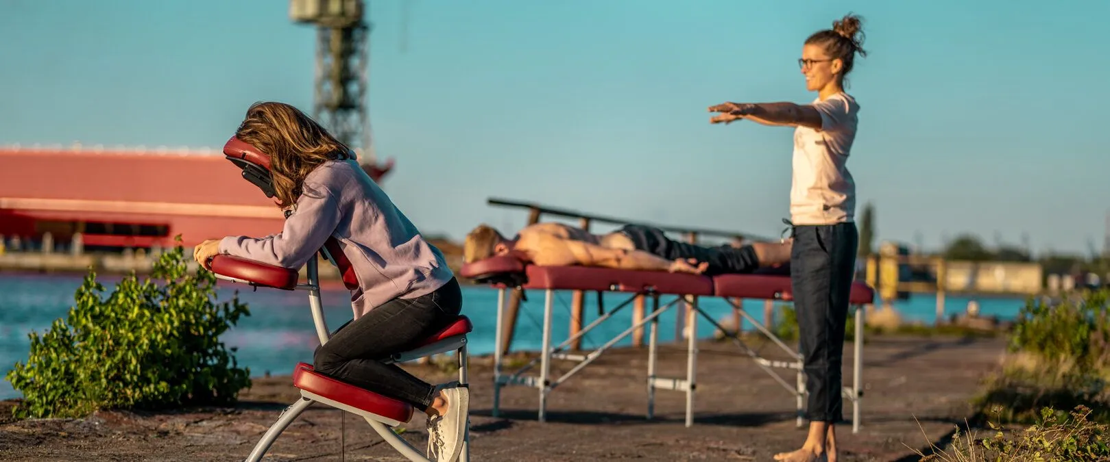 Masaż na krześle i na stole do masażu w plenerze nad wodą